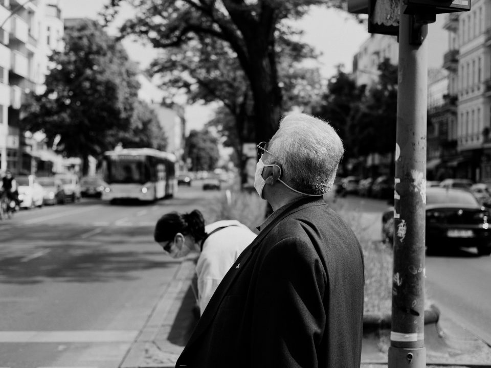 man in black suit standing on sidewalk in grayscale photography