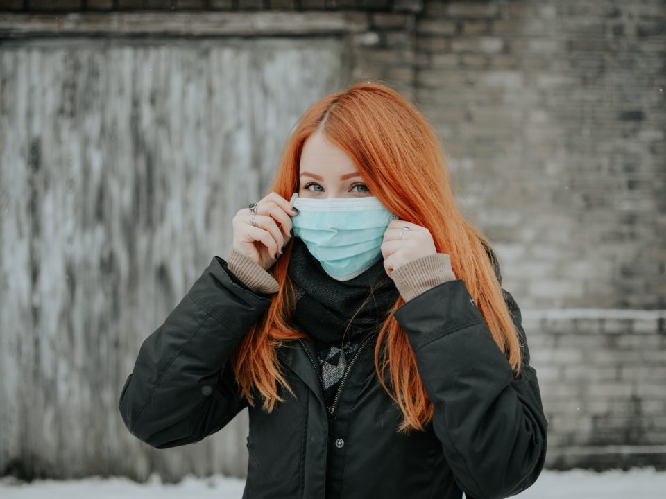 woman in black jacket covering her face with white ceramic mug