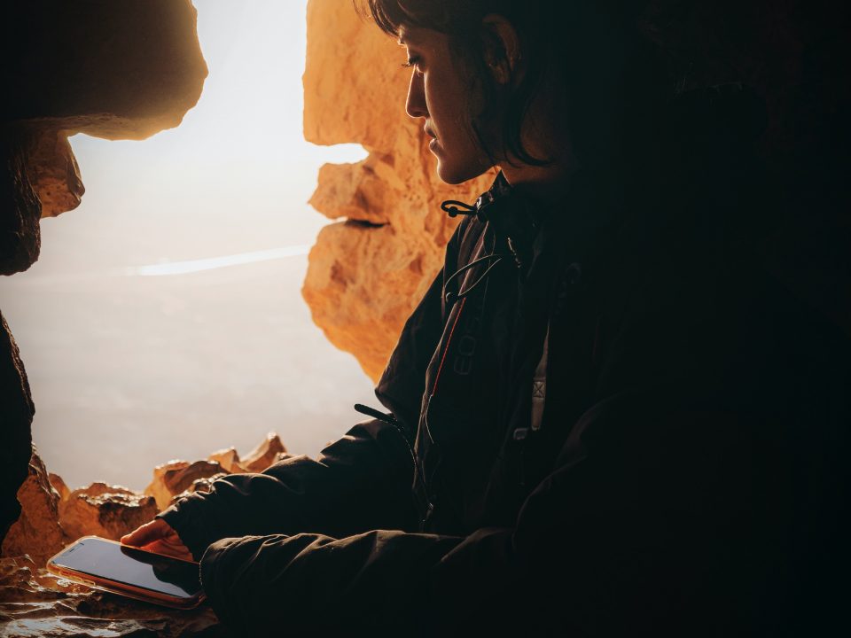 woman in black jacket sitting on rock formation during daytime