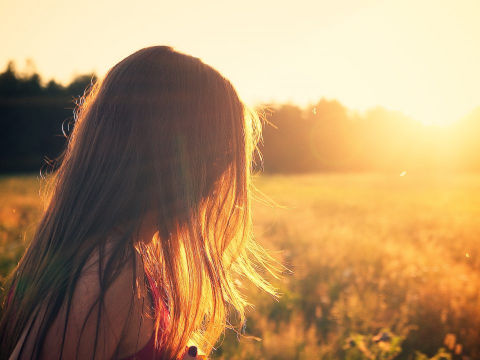 woman wearing black camisole top walking on grass field during sunrise