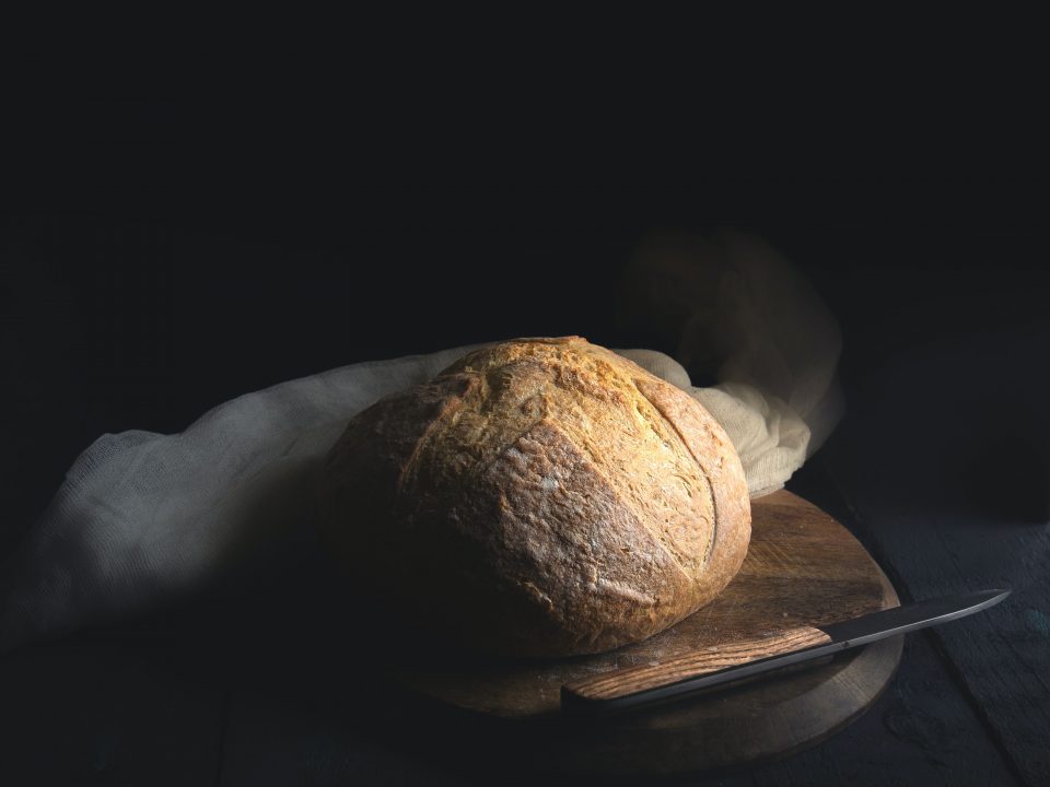 baked bread beside knife on wooden board