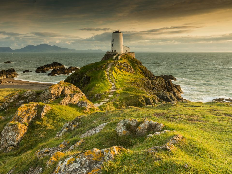 white concrete lighthouse on cliff beside sea under clear blue sky during daytime