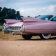 vintage pink muscle car parked near field of grass