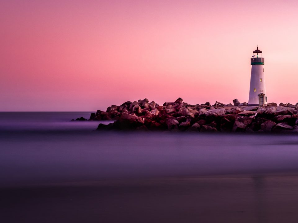 white lighthouse on rocky seashore