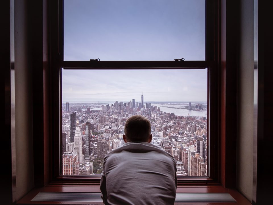 man in gray shirt looking at city buildings during daytime