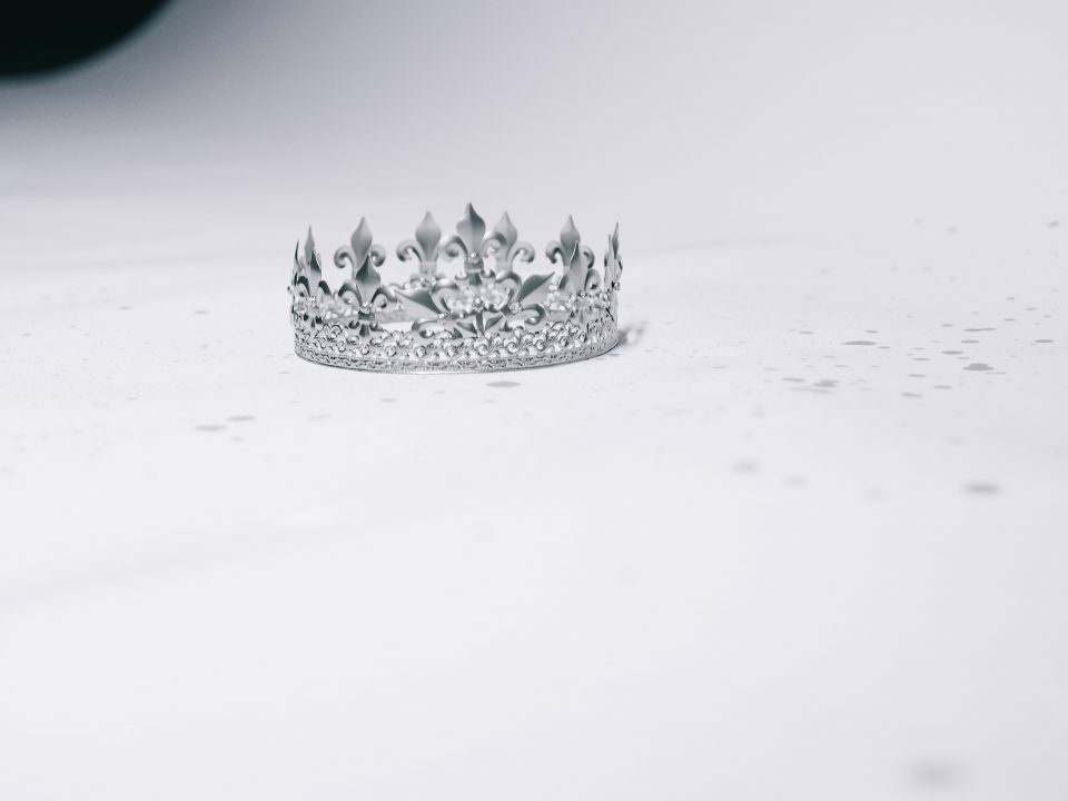 silver-colored crown ring on white surface