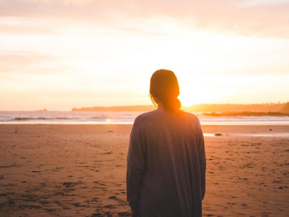 woman standing on sand and facing at seashore