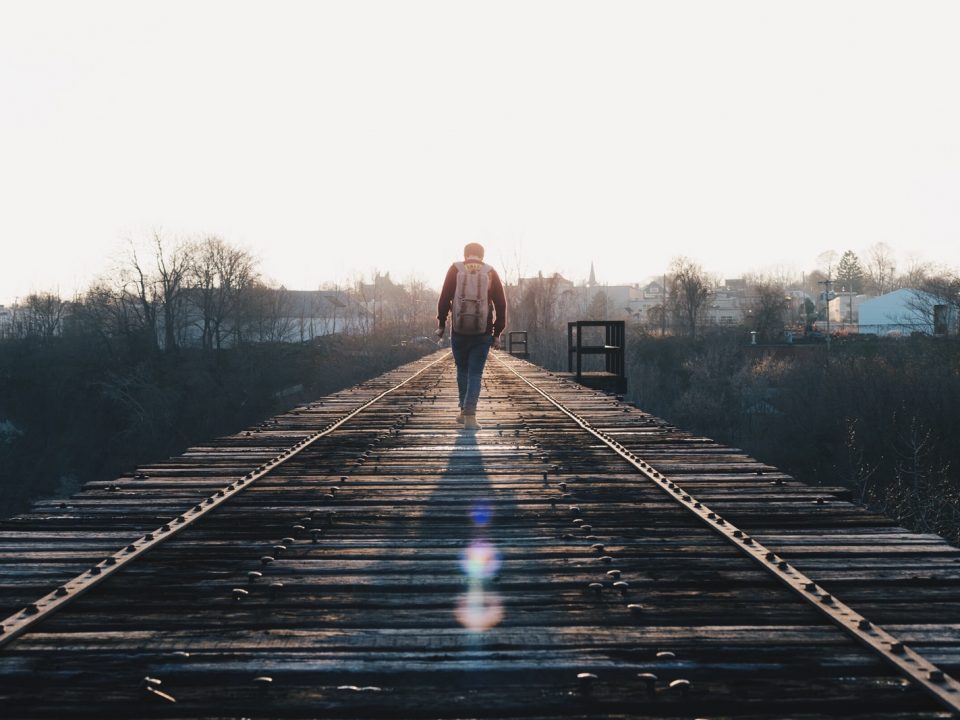 man walking in the middle of rail road