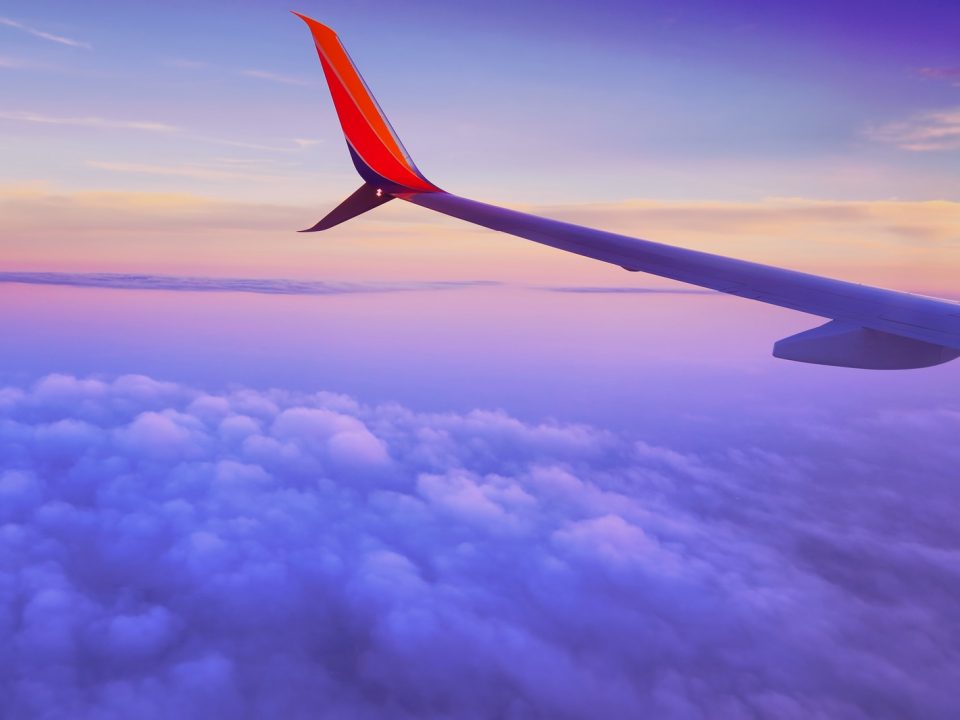 person in a plane flying at high altitude taking photo of left airplane wing during daytime