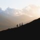 silhouette of 2 people standing on mountain during daytime