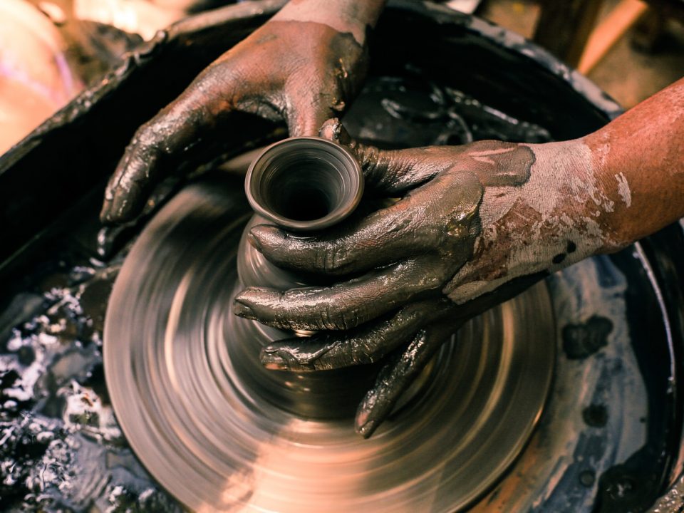 person making clay pot with water