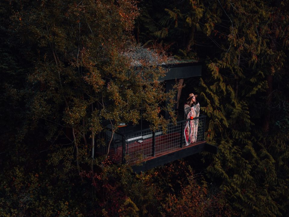 woman in red and white plaid dress shirt standing on brown wooden bridge