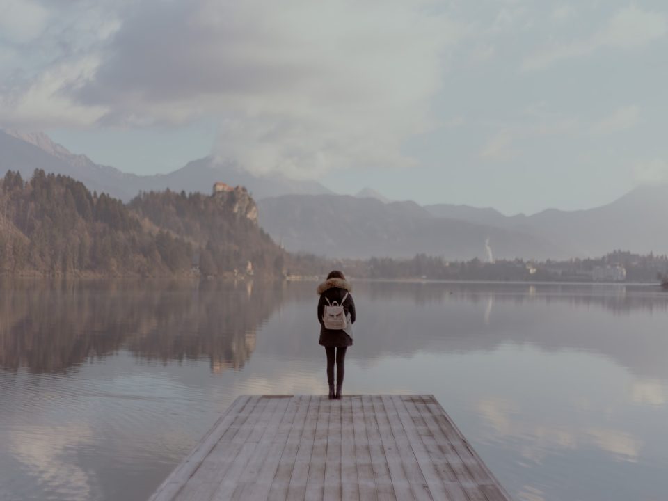 woman standing beside body of calm water