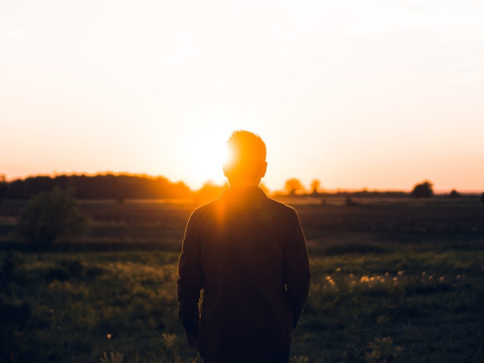 silhouette of man facing sunset