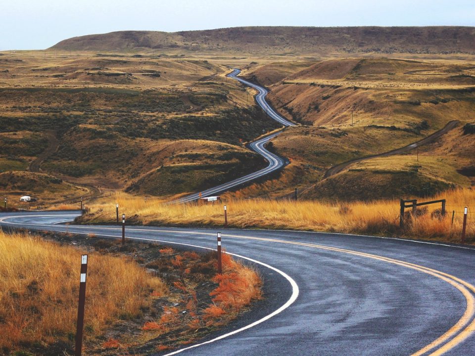 gray concrete road across brown valley during daytime