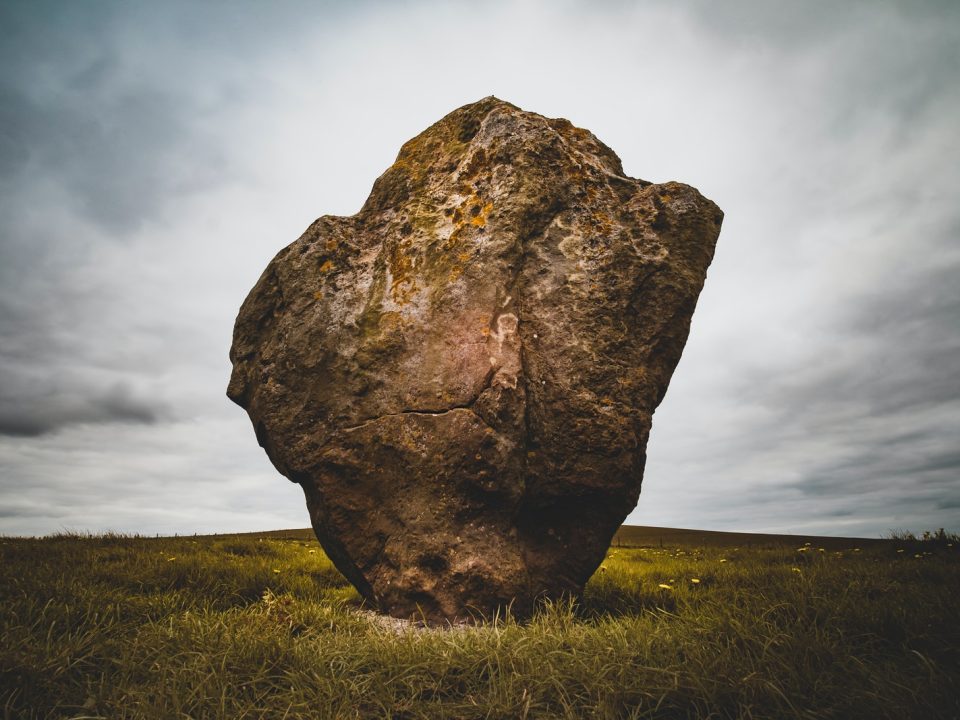 brown rock formation surrounded by green grass