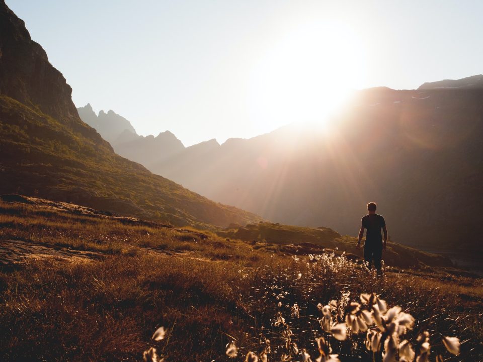 man walking beside the foot of the mountain during daytime