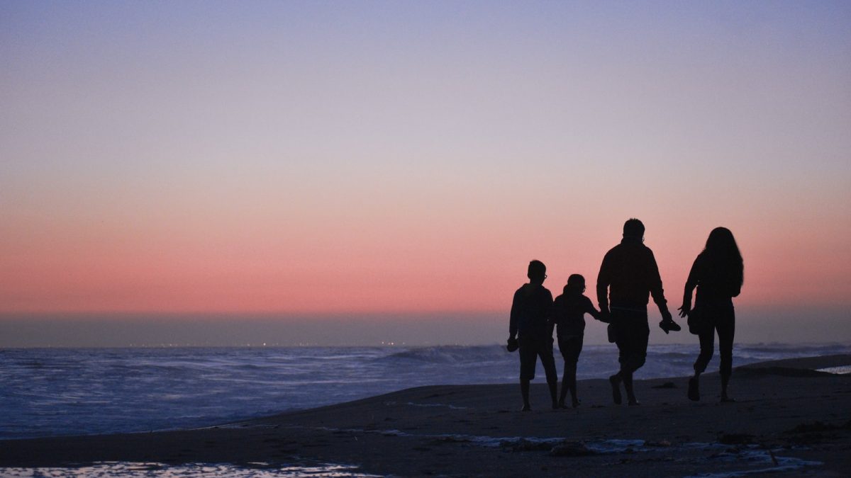 silhouette of 3 men and woman standing on beach during sunset