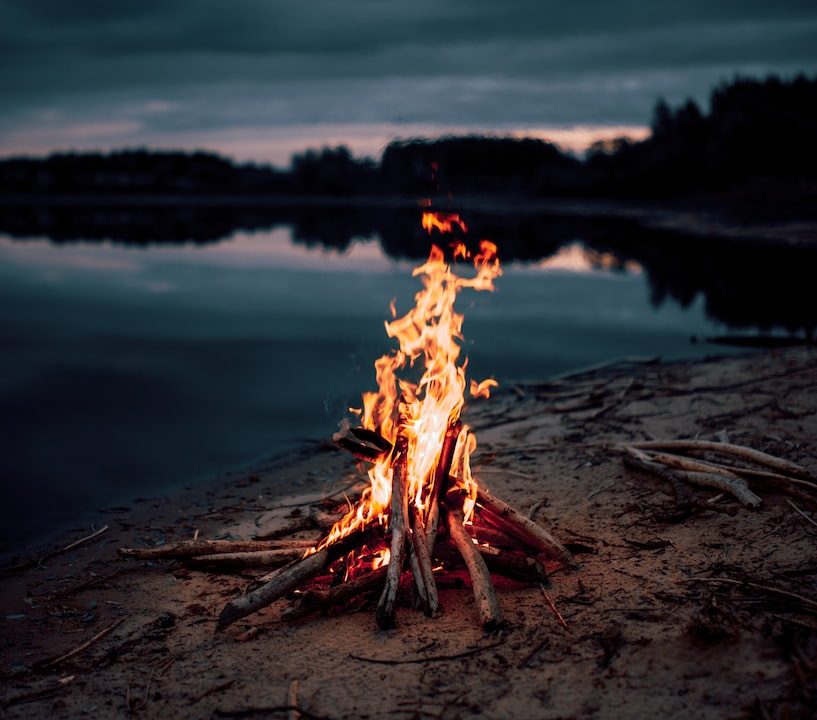 bonfire near body of water during night time