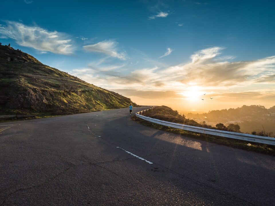 person running on road street cliff during golden hour