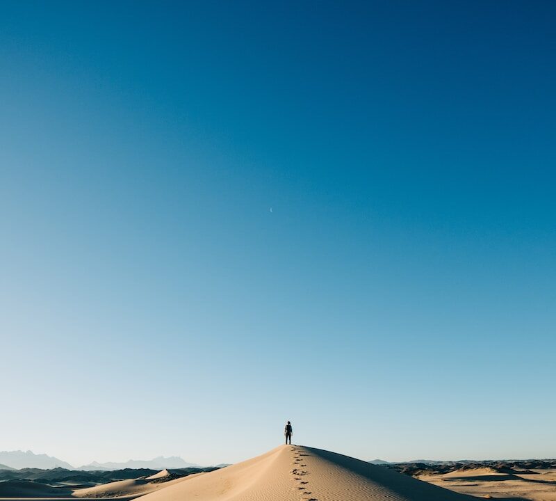 a person standing on top of a sand dune