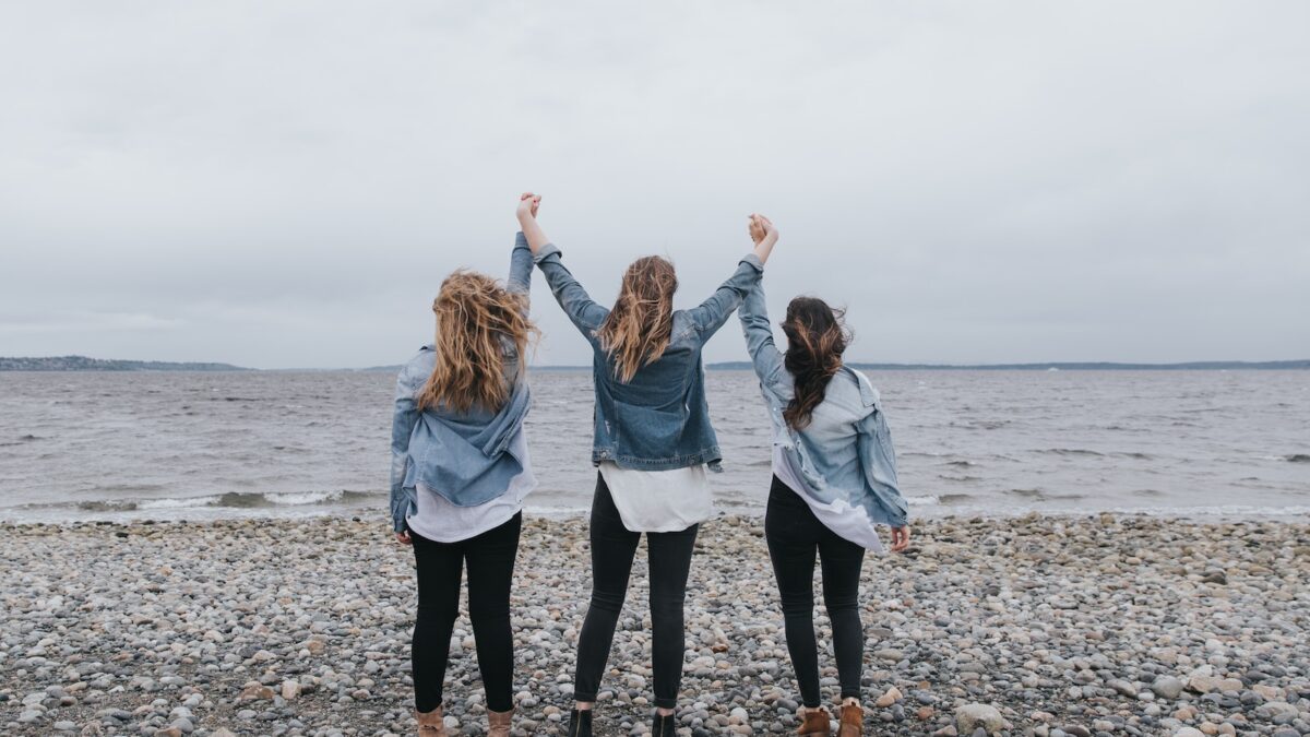 4 women standing on beach during daytime