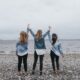 4 women standing on beach during daytime