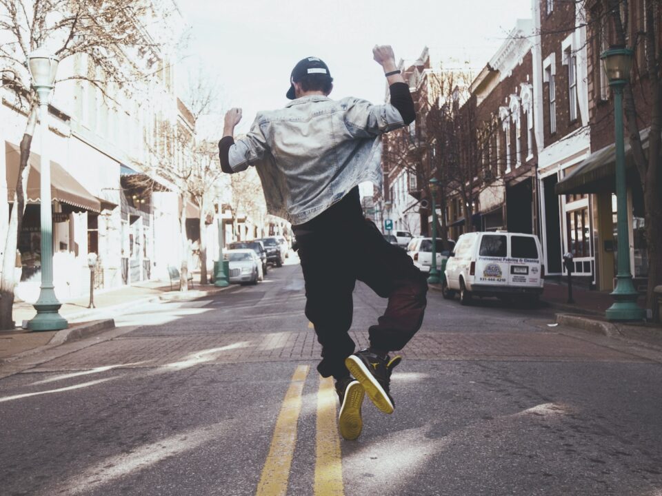 man jumping on the middle of the street during daytime