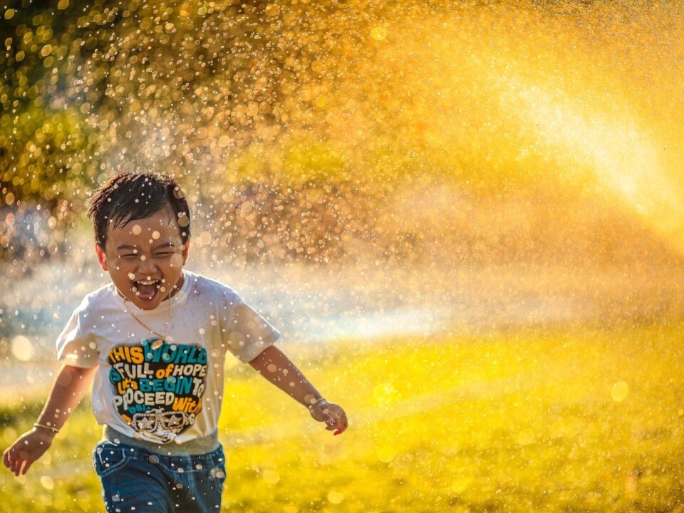 a young boy running through a sprinkle of water