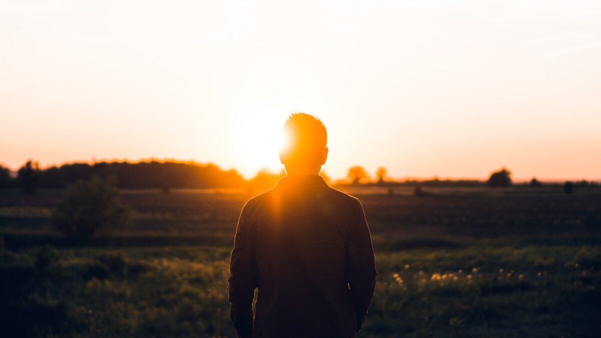 silhouette of man facing sunset