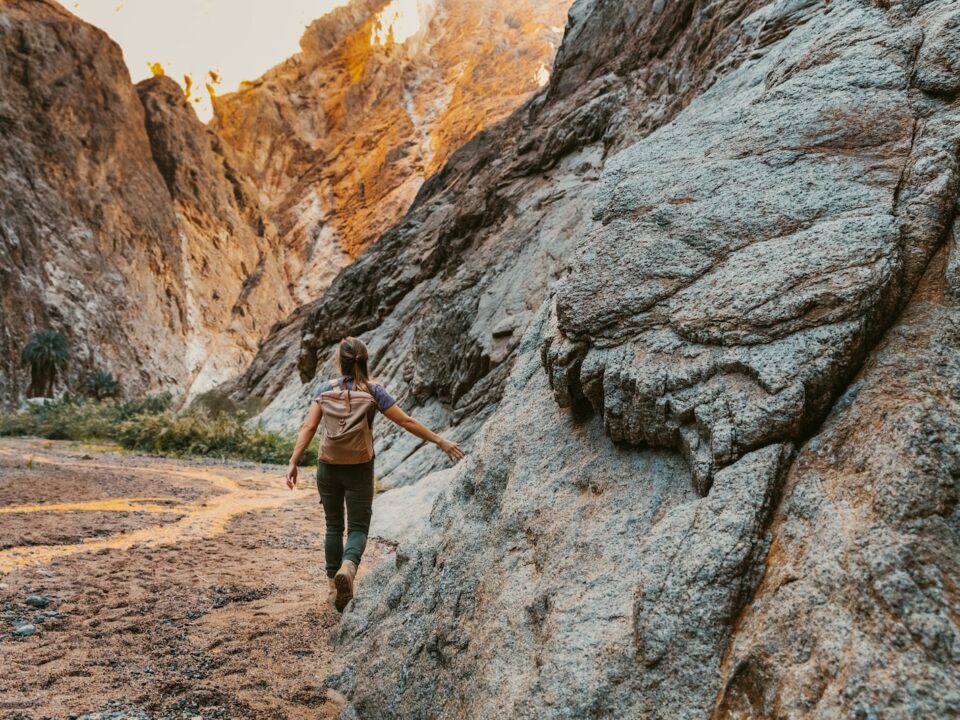 a woman climbing up a large rock in the mountains