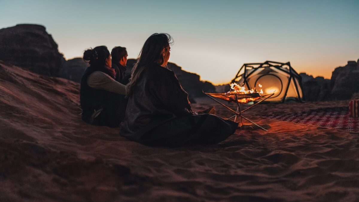 a group of people sitting on top of a sandy beach