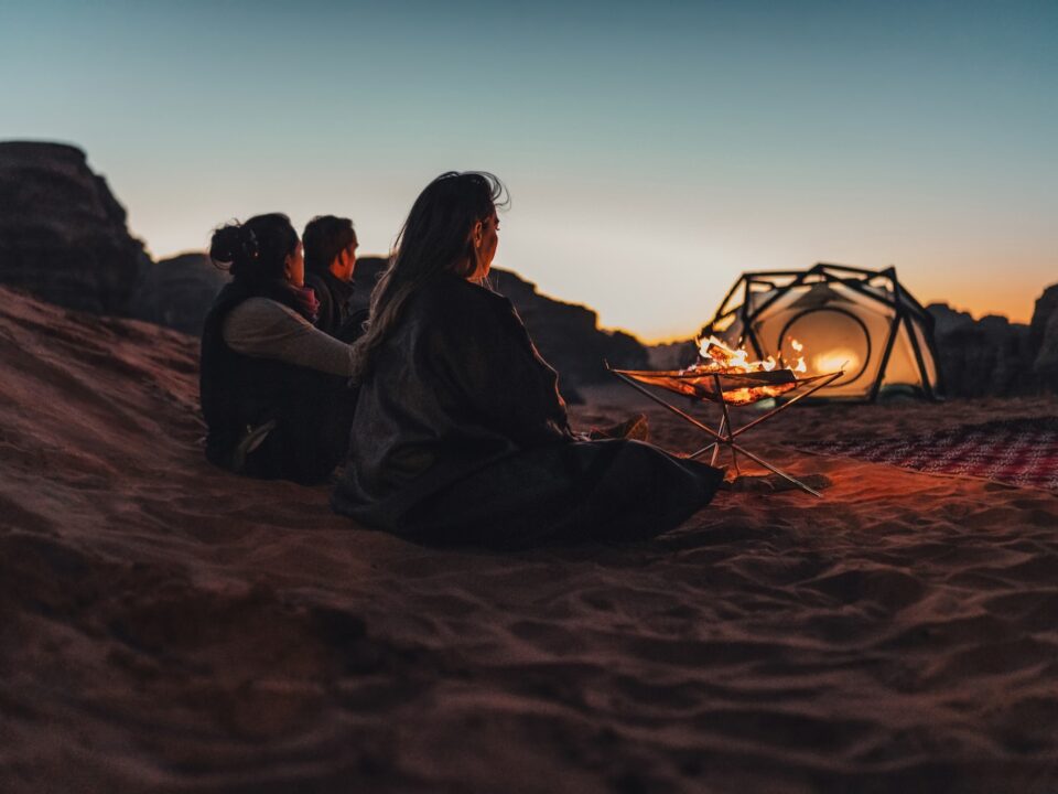 a group of people sitting on top of a sandy beach