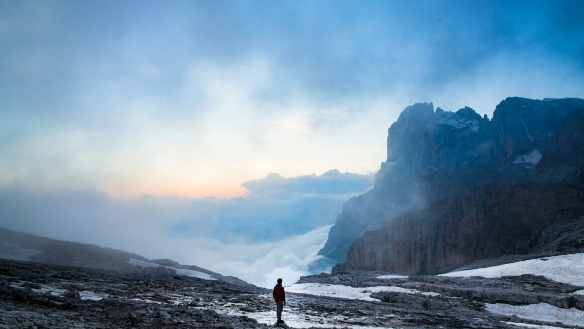 person standing near the cliff of the mountain