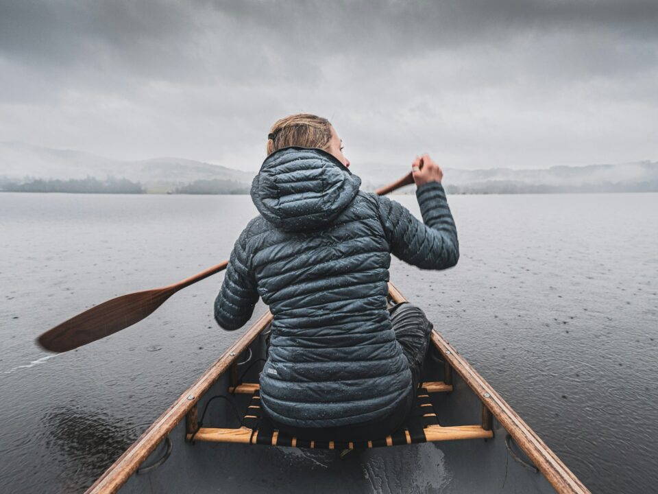 a woman paddling a canoe on a lake