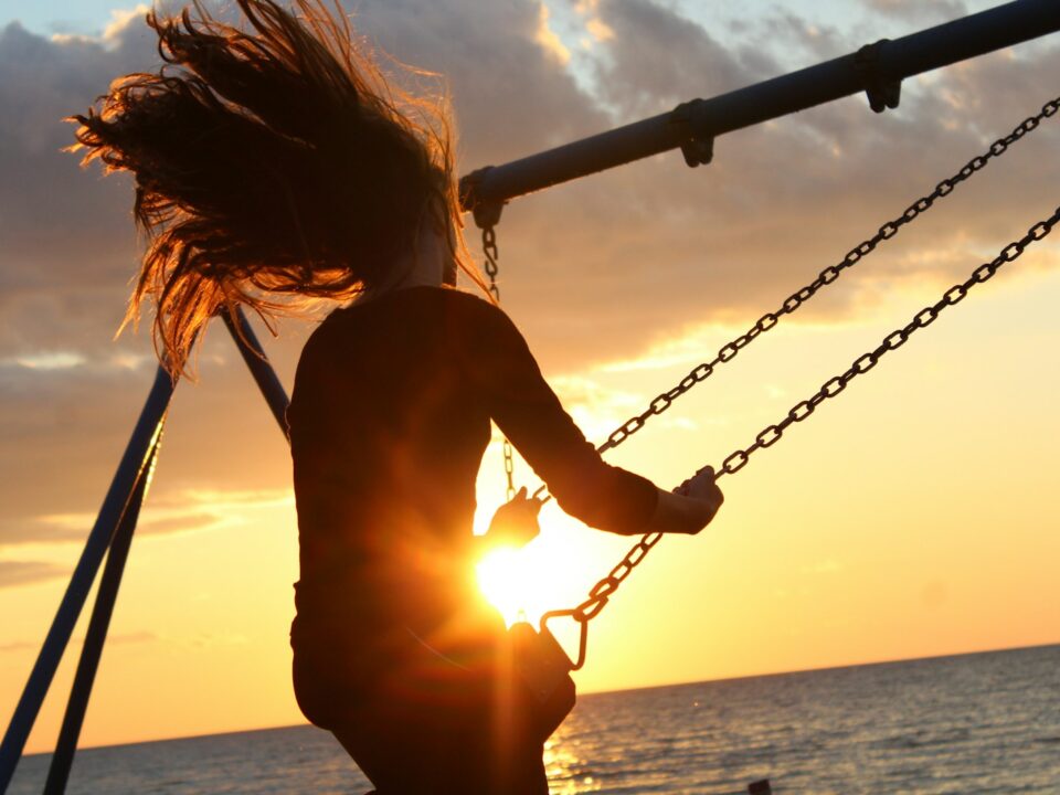 woman riding on swing during sunset