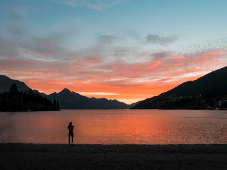 silhouette photo of woman standing while facing body of water