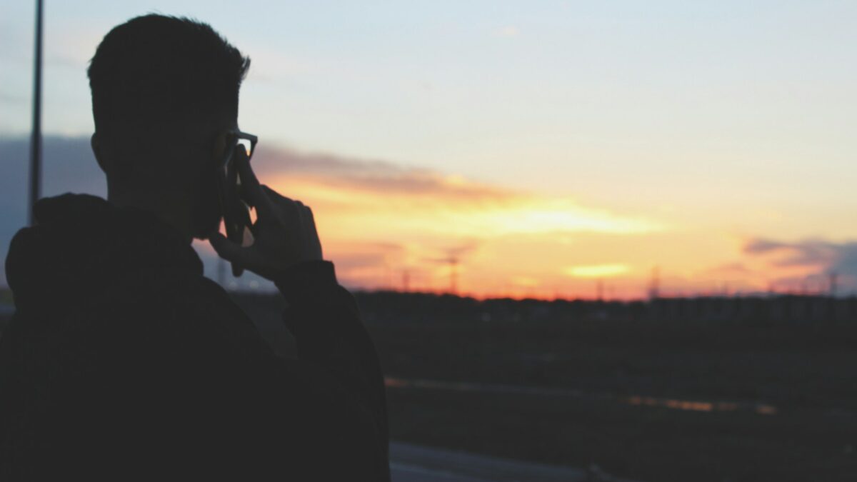 man using phone near road during daytime