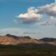 a mountain range with a few clouds in the sky