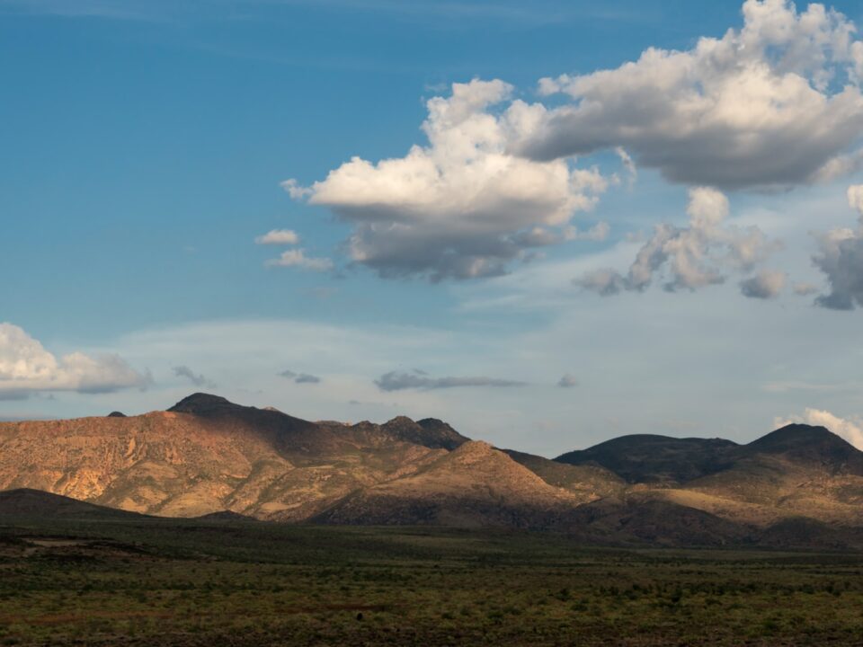 a mountain range with a few clouds in the sky