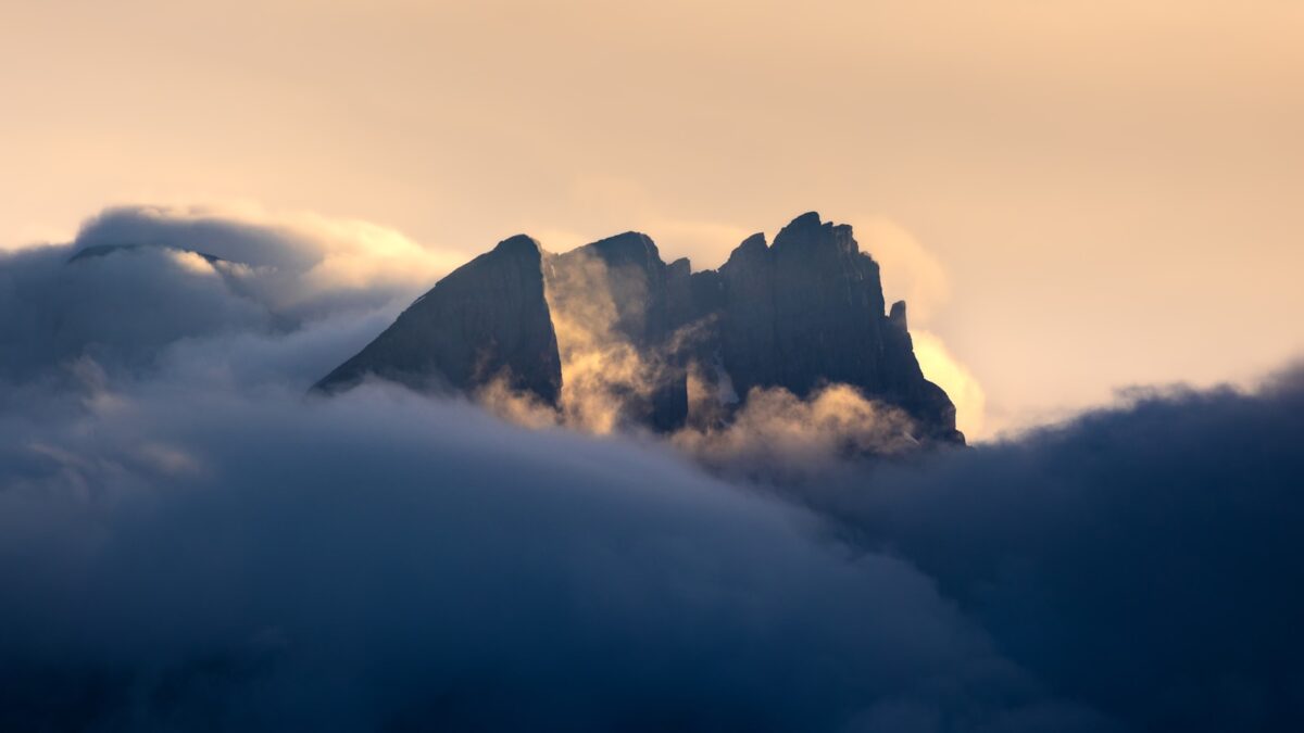 A mountain covered in clouds with a sky background