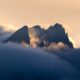 A mountain covered in clouds with a sky background