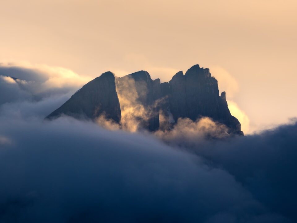 A mountain covered in clouds with a sky background