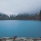 man standing on cliff facing bod of water