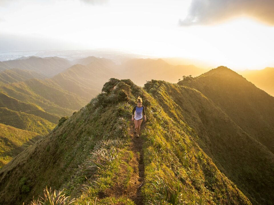 woman walking on pathway on top of hill at golden hour