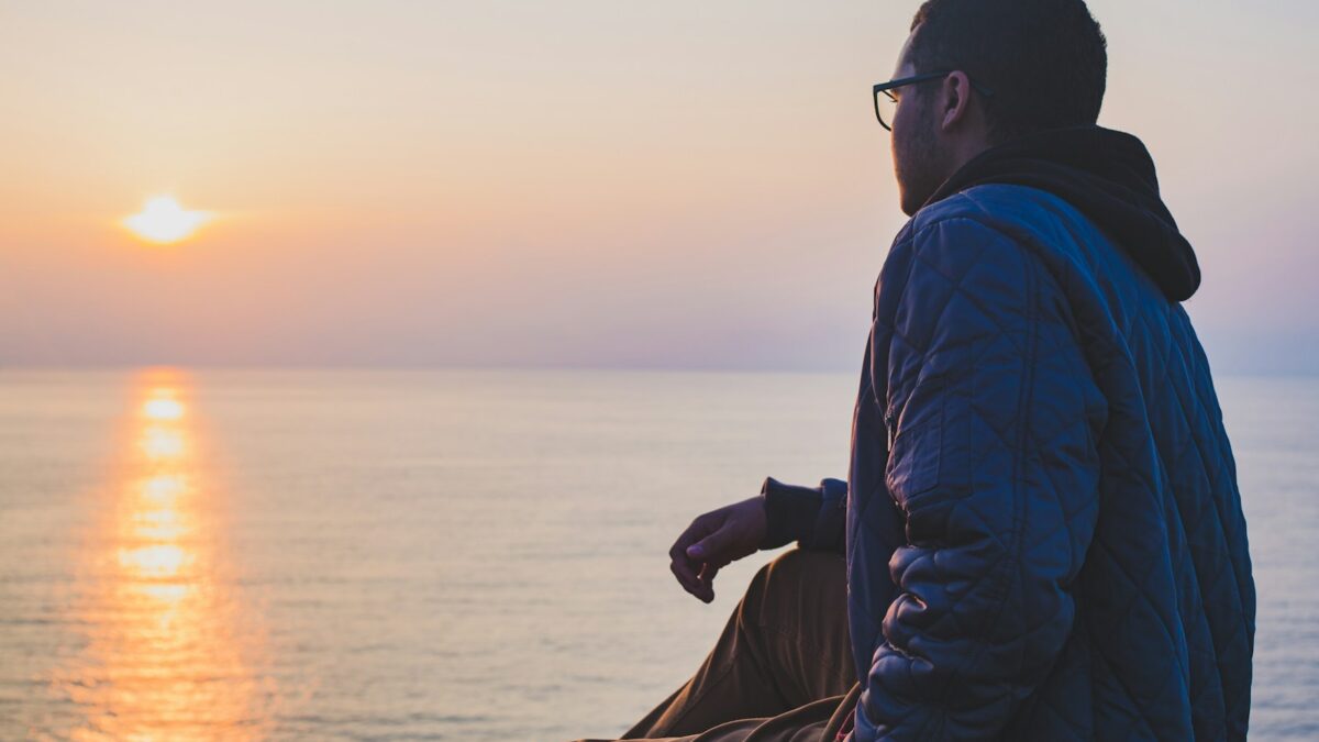 man sitting near body of water