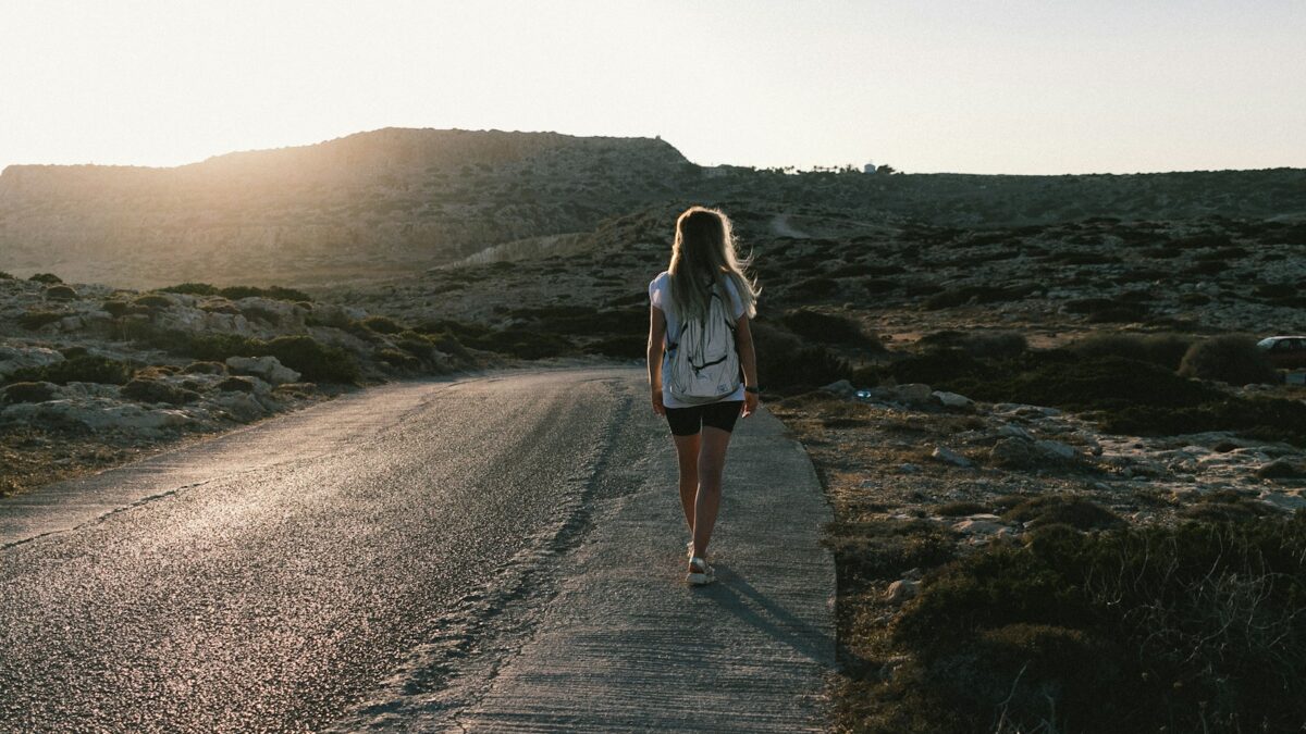 a woman walking down a road in the desert