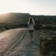 a woman walking down a road in the desert