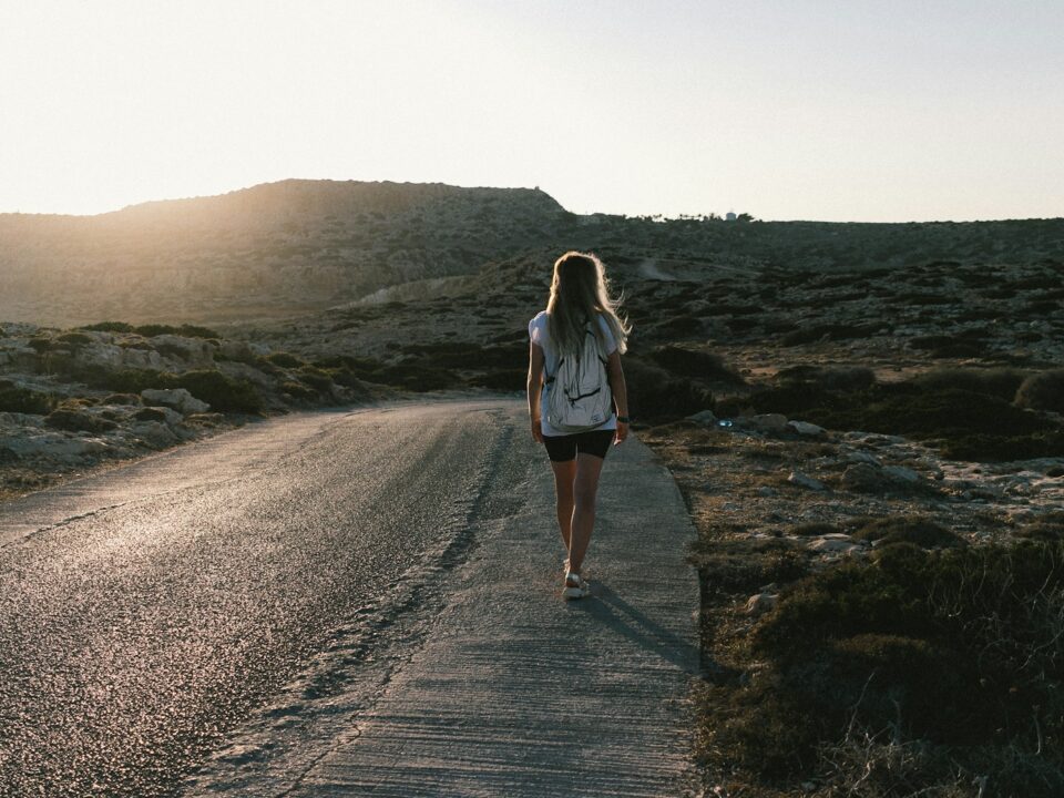 a woman walking down a road in the desert