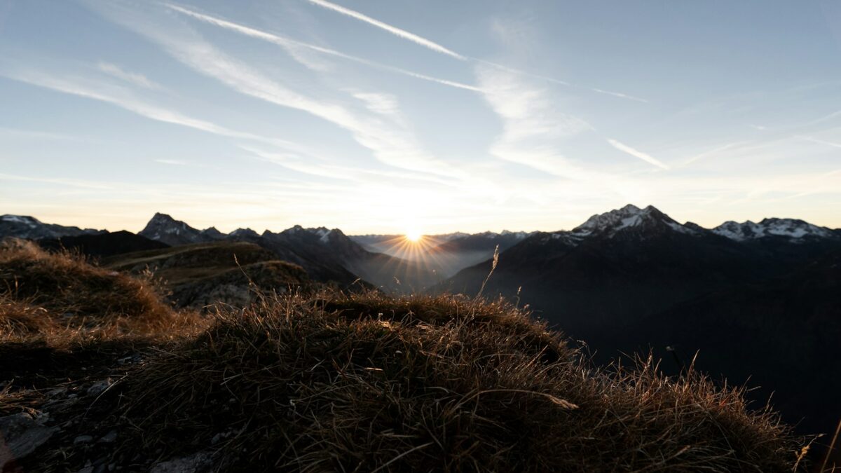 the sun is setting over a mountain range